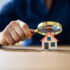 Image of a person holding a magnifying glass over a small house