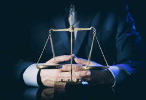 Image of the scales of justice on a table with an attorney in the background
