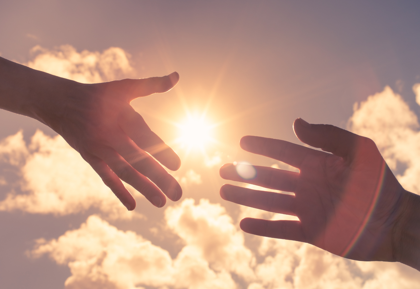 Image of two hands reaching for each other in front of a cloudy sky