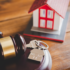 Image of a gavel, a key, and a miniature of a house on a desk