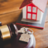 Image of a small house, a gavel, and set of keys on a desk