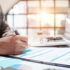 Image of a person writing on a document at a desk